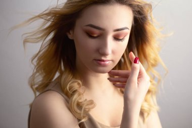 güzel bir genç kadının yumuşak stüdyo portresi, rüzgardan darmadağınık kıvırcık saçlı kız yüzü, doğal güzellik kavramı, vücut bakımı, kozmetik