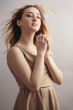 güzel bir genç kadının yumuşak stüdyo portresi, rüzgardan darmadağınık kıvırcık saçlı kız yüzü, doğal güzellik kavramı, vücut bakımı, kozmetik