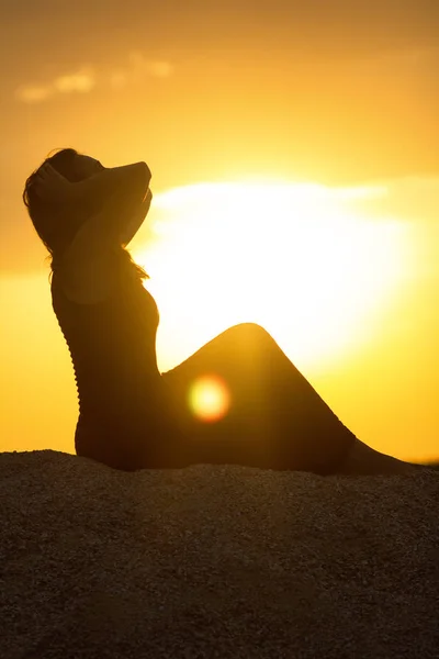 美しい思慮深い少女のシルエット砂の上に座って夕日を楽しんでビーチで若い女性の姿自然を瞑想女性 — ストック写真