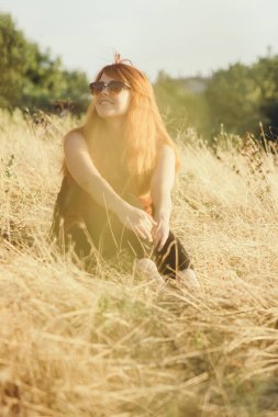 omuzlarında bir sırt çantası ile genç kız bir alanda oturan ve gün batımı zevk, yürüyüş kavramı, yürüyüş, dinlenme, aktif yaşam tarzı