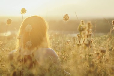 kurutulmuş çiçekler arasında bir alanda yerde oturan kırmızı saçlı kız baş ve gün batımında doğa sahiptir, genç kadın rahatlatıcı, dinlenme kavramı, sağlık, uyum, yaşam tarzı