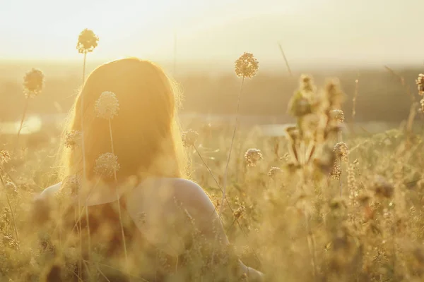 Cabecera de chica pelirroja sentada en el suelo en un campo entre flores secas y disfruta de la naturaleza al atardecer, mujer joven relajante, concepto de descanso, salud, armonía, estilo de vida — Foto de Stock