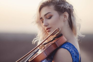 Çenesinin altında keman olan romantik bir genç kadının portresi. Yüzü, doğa, konsept hobi ve yaşam tarzıyla yalnızlık içinde dinleniyor.