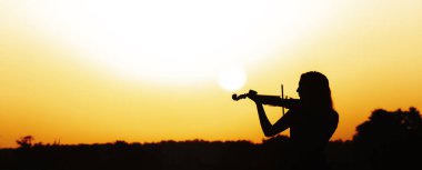 Şafakta nehir kıyısında kemanı olan genç bir kadının romantik silueti, doğa, konsept müzik ve ilham üzerine müzik çalan zarif bir kız.