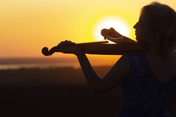 Perfil facial silueta de una figura femenina tocando el violín al atardecer, chica disfrutando de su actuación en la naturaleza, concepto de arte musical e inspiración — Foto de Stock