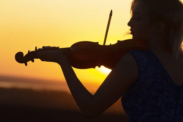 Arc profil sziluett egy női alak hegedül naplementekor, előadás a természetben, lány hangszerrel az álla alatt, koncepció zenei művészet — Stock Fotó