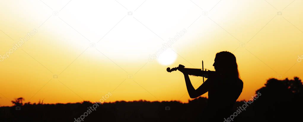 romantic silhouette of young woman with a violin at dawn on river bank, elegant girl playing a musical instrument on nature, concept music and inspiration
