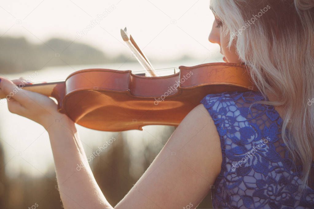 romantic young woman playing violin on river bank, girl relaxing in solitude, performance on nature, concept hobby and music