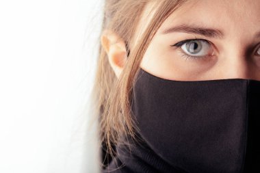 2020 'de karantina ve salgın altında siyah bir maske takan üzgün genç bir kadının yüzü.,