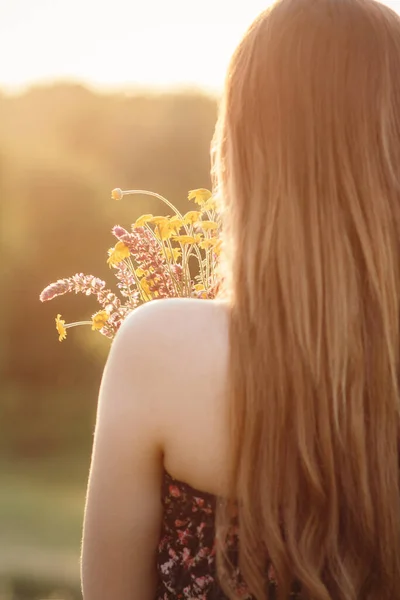 草原に野の花の花束を持つ美しい女の子 自然の上を歩くドレスで長い髪の若い女性 村の夏の柔らかい写真 — ストック写真