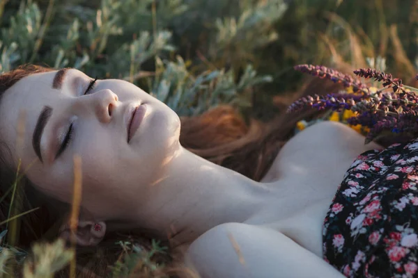 美丽的女孩脸庞紧贴着野花束躺在草地上 年轻女子一头长发在大自然中 夏天在村子里拍着温柔的照片 — 图库照片