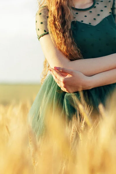 緑のドレスの美しい女性がフィールドに歩いて 日没の光で手で小麦の耳に触れ 女の子は夏の自然景観を楽しんで — ストック写真
