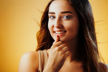 Turuncu arka planda yüzü olan güzel bir kız, genç kadın portresi, kadın güzelliği konsepti.