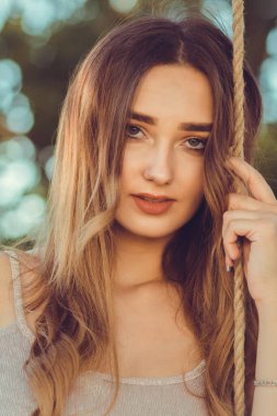 Salıncak iplerinin yanında güzel, baştan çıkarıcı bir kadının portresi, doğada yürüyen bir kız, genç bir kadın eğlence aktivitesi, yaşam tarzı konsepti