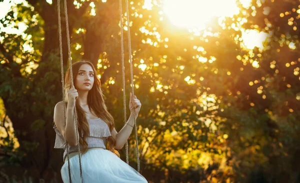 夏の大自然の中でロープスイングで長い髪のスイングを持つ美しい女の子Arの夕日 若い女性は木の枝の間で飛行を楽しむ レジャー活動 ライフスタイルコンセプト — ストック写真