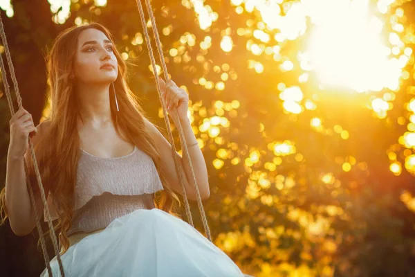 夏の大自然の中でロープスイングで長い髪のスイングを持つ美しい女の子Arの夕日 若い女性は木の枝の間で飛行を楽しむ レジャー活動 ライフスタイルコンセプト — ストック写真