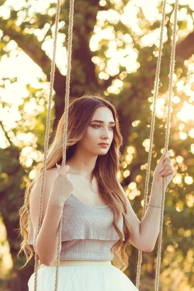 夏の大自然の中でロープスイングで揺れる長い髪を持つ美しい女の子 若い女性は日没でリラックス レジャー活動 ライフスタイルコンセプト — ストック写真