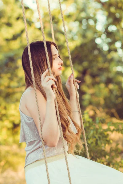夏の大自然のロープスイングで長い髪のスイングを持つ美しい女の子 若い女性がリラックス レジャー活動 ライフスタイルの概念 — ストック写真