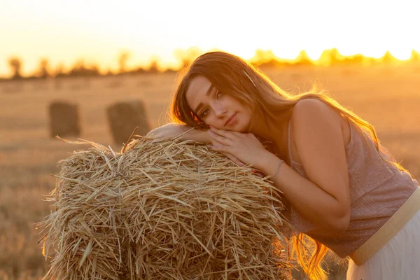 夏天的傍晚 年轻的女人靠在草堆上散步 美丽而浪漫的姑娘 黄昏时分 她的长发在田野里 — 图库照片