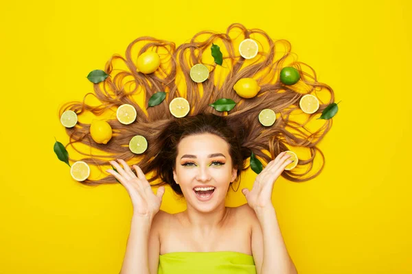 Счастливая Девушка Лежит Ярко Желтом Фоне Цитрусовыми Фруктами Длинных Волосах — стоковое фото