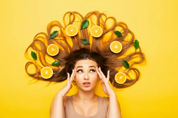 Вдумчивая Девушка Лежит Студийном Фоне Апельсиновыми Фруктами Длинных Волосах Молодая — стоковое фото