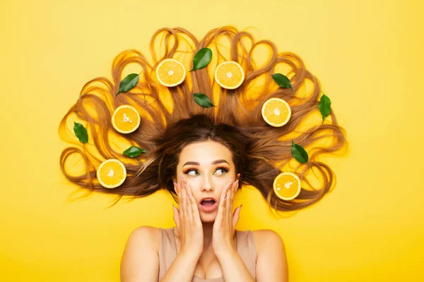 Удивленная Девушка Лежит Ярком Студийном Фоне Апельсиновыми Фруктами Длинных Волосах — стоковое фото