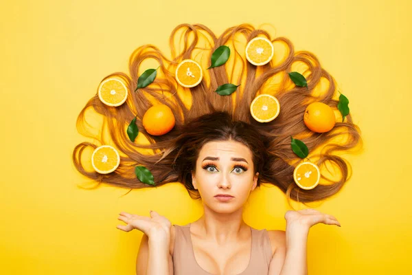 Красивая Смущенная Девушка Лежит Студийном Фоне Апельсиновыми Фруктами Длинных Волосах — стоковое фото