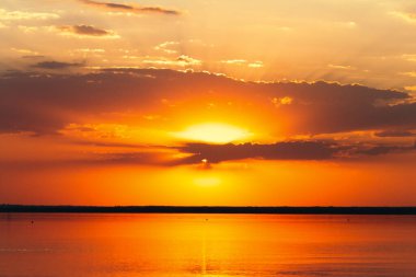 Deniz ufkunda gün batımının arka planı, güneş ışınlarıyla aydınlatılan bulutlar, güzel manzara, su üzerinde yüzen kuşlar.