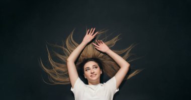 Siyah stüdyo arka planında uzanan genç bir kadın ve rahatlatıcı, rüya gören kız öğrenci manzarası.