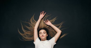 Siyah stüdyo arka planında uzanan genç bir kadın ve rahatlatıcı, rüya gören kız öğrenci manzarası.