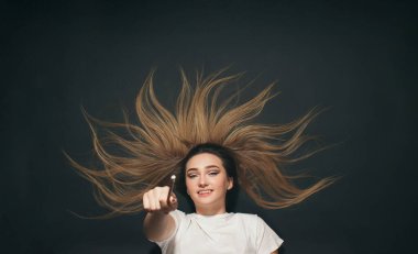 Siyah stüdyo arka planında uzanan mutlu genç bir kadın, kameraya kalemle bakan öğrenci kız, başarı ve kararlılık kavramı.