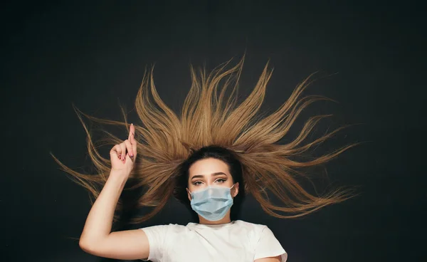 녹음실 위에서 얼굴을 보호하는 의료용 마스크를 여성이 손가락을 내밀어 발표를 — 스톡 사진