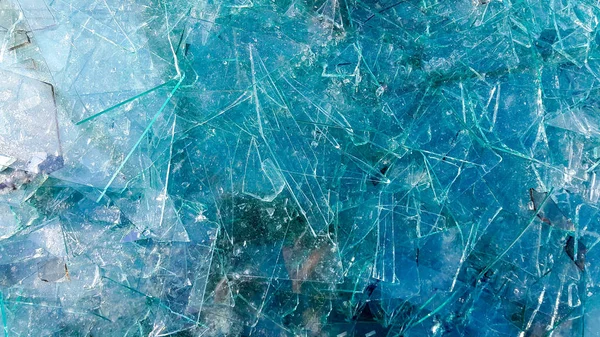 Kırık cam yakın plan. Pencereden kırılan küçük cam parçaları. Vandalizm özel mülkü tehdit eder. Soyut mavi arkaplan
