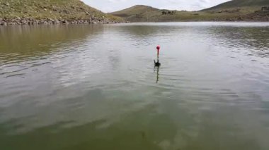 Suda yüzen bir balıkçı teknesi. Şamandıra ısırıktan hareket ediyor. Gölde dinlenme. Balık tutma kavramı. Balıkçılık malzemeleri. Hobiler ve eğlence.