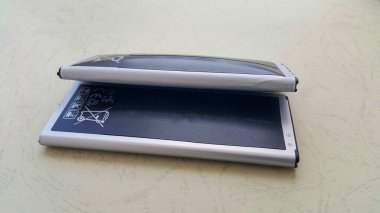 İki yakın çekim pil, biri normal diğeri de şişmiş lityum iyonlu akıllı telefon pili. Hasarlı bir batarya yanmaya ya da patlamaya hazır. Boşluğu Kopyala.