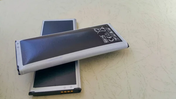 İki yakın çekim pil, biri normal diğeri de şişmiş lityum iyonlu akıllı telefon pili. Hasarlı bir batarya yanmaya ya da patlamaya hazır. Boşluğu Kopyala.