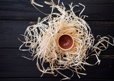 Siyah ahşap masa üzerinde saman yuvadaki küçük piala