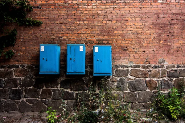 Τοίχος από κόκκινα τούβλα με τρία μπλε κουτιά — Φωτογραφία Αρχείου