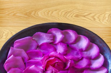 Ahşap zemin üzerine pembe ve beyaz güller. Bir kase içinde doğal çiçekler.