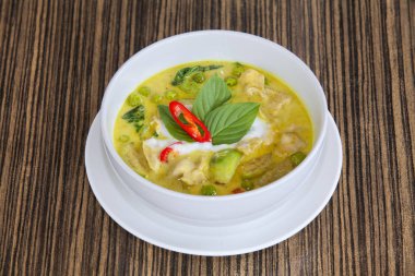 yeşil köri Balık top (Tay gıda) Beyaz plaka üzerinde ahşap masa, lezzetli bir görünüm.