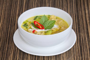 yeşil köri Balık top (Tay gıda) Beyaz plaka üzerinde ahşap masa, lezzetli bir görünüm.