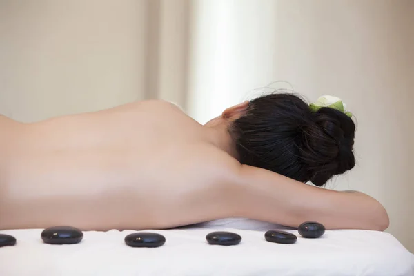 Beautiful woman having hot stones on her back in spa salon. concept of healthcare and female beauty. view of the woman\'s back with hot stones from the front