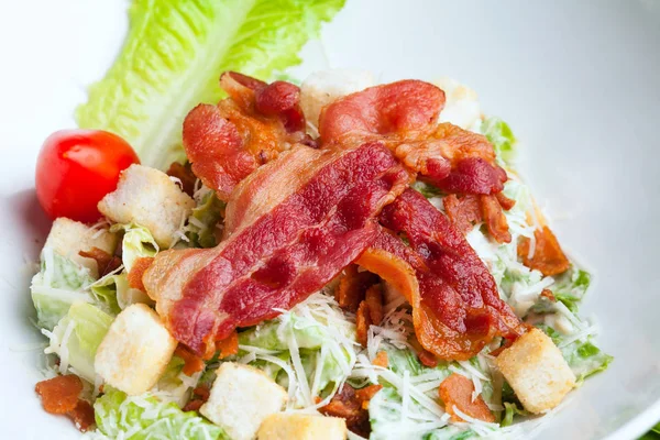 Sezar salatası gevrek domuz pastırması fry ve taze yeşil çünkü beyaz arka plan üzerinde izole marul.