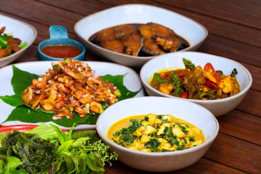 Tahta masaya konmuş tek kızartılmış güneşli kartal balığı dilimleri, körili yengeç eti, sebze ve körili tavuk..