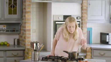 Mutfakta genç kadın yemek ve yardım için cep telefonu kullanarak