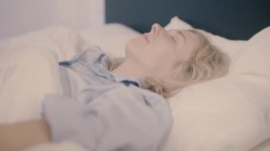 Genç kadın yatakta uyanık ve bir gülümseme ile germe yatıyordu 