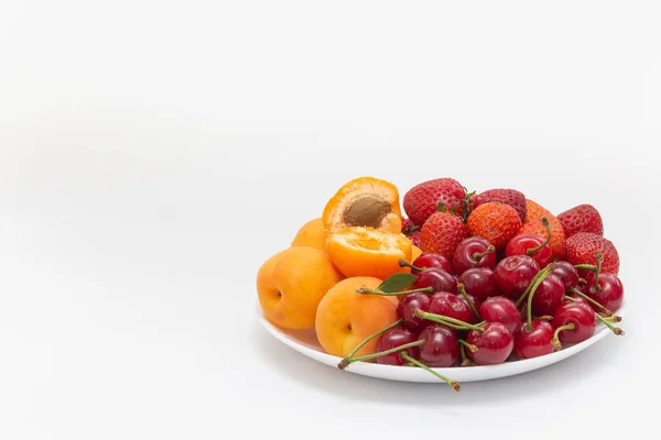 Diverse vruchten in witte schaal geïsoleerd op witte achtergrond. Schaal gezond vers fruit. Bovenaanzicht. Aardbei, kers, abrikoos. Hoge kwaliteit foto — Stockfoto