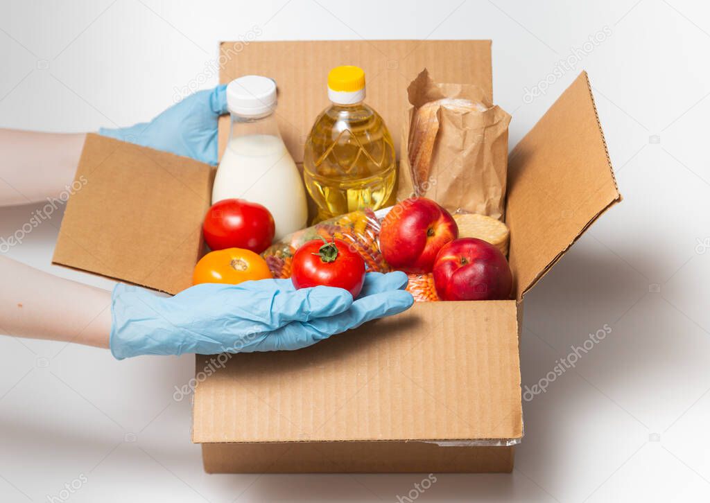 Person in latex gloves has holding a box with ordered goods.Safe food delivery service under quarantine. Online food shopping service or donation concept. White background.High quality close up photo