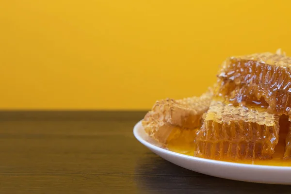 Honeycombs i vit tallrik på träbordet. Naturlig ekologisk biprodukt. En hälsosam livsstil. Kopiera utrymmet för ditt sms. Närbild foto. — Stockfoto