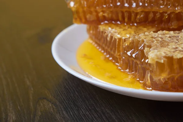 Honeycombs i vit tallrik på träbordet. Naturlig ekologisk biprodukt. En hälsosam livsstil. Kopiera utrymmet för ditt sms. Närbild foto. — Stockfoto